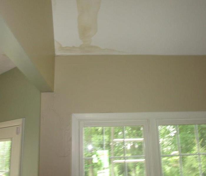 A white ceiling with large dark water marks 
