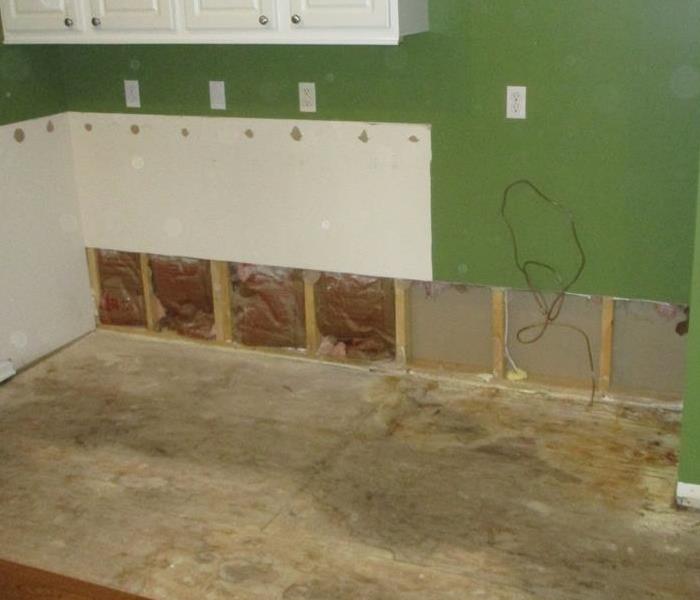 Water Damaged kitchen with exposed sub floor, drywall on perimeter is missing and insulation behind drywall is missing