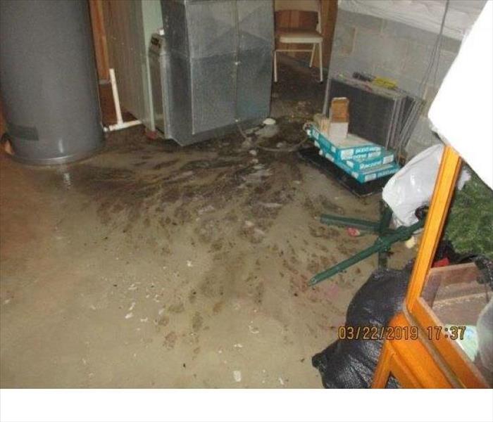 Basement utility room with concrete flood covered with water containing raw sewage